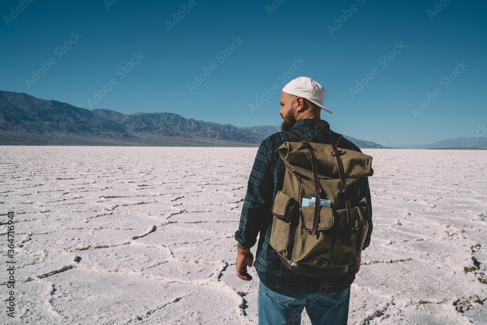 Male traveler having trip to unique natural environment in california walking on desolated arid surface,back view of man with rucksack walking in Death Valley exploring landscape and environment Male traveler having trip to unique natural environment in california walking on desolated arid surface,back view of man with rucksack walking in Death Valley exploring landscape and environment