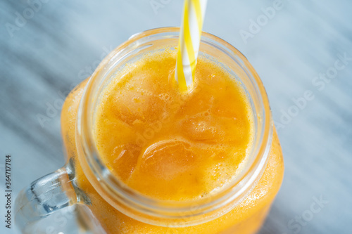 Fresh organic yellow smoothie in glass mug on white wooden table, close up. Refreshing summer fruit drink. The concept of healthy eating. Sea buckthorn smoothie