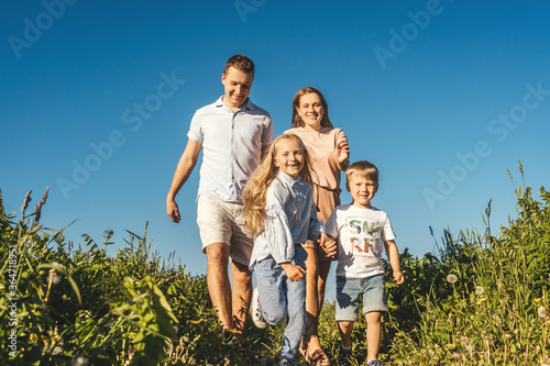 Happy family of mother, father and two children have a fun and run in field.