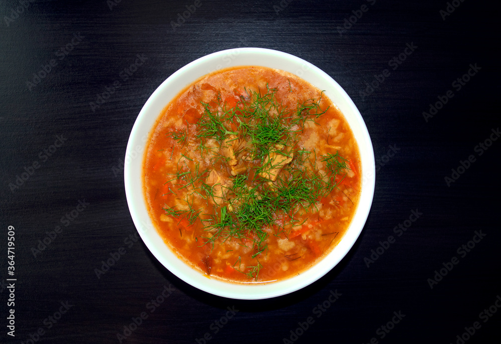 Kharcho soup in a white bowl on dark wooden background. Top view. Famous traditional Georgian kharcho soup with beef, rice and tomatoes. Georgian lamb and rice soup