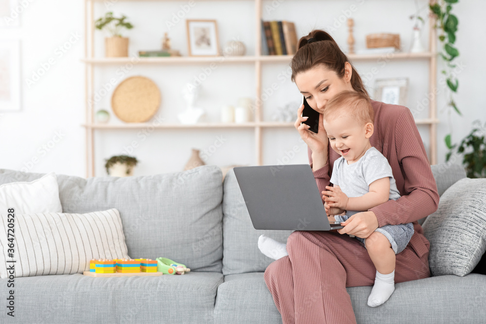 Balancing Work And Motherhood. Woman using cellphone and laptop while holding baby Balancing Work And Motherhood. Woman using cellphone and laptop while holding baby