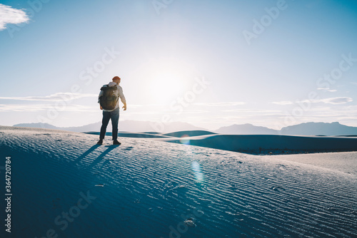 Back view of young male traveler exploring white sand desert on active vacation recreation, man explorer looking at beautiful scenery of sunset enjoying discover destination of wild environment