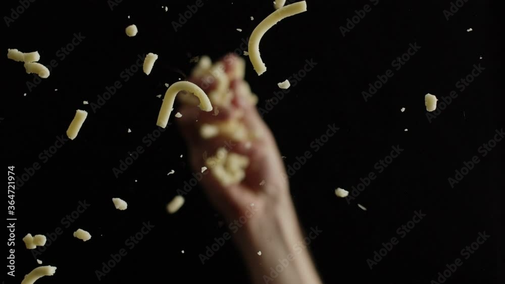 Crop chef dropping ground cheese on camera