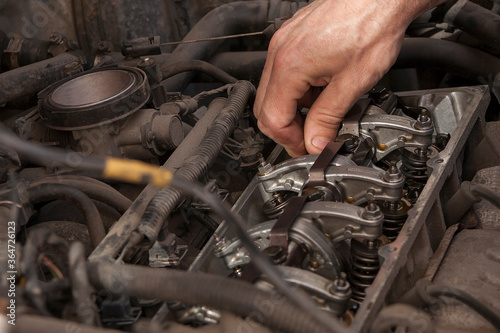hand checks engine valves in old car