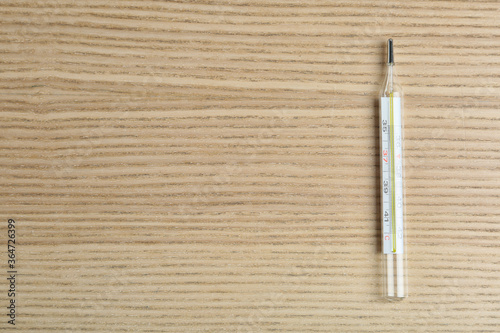 Mercury thermometer on wooden table, top view. Space for text