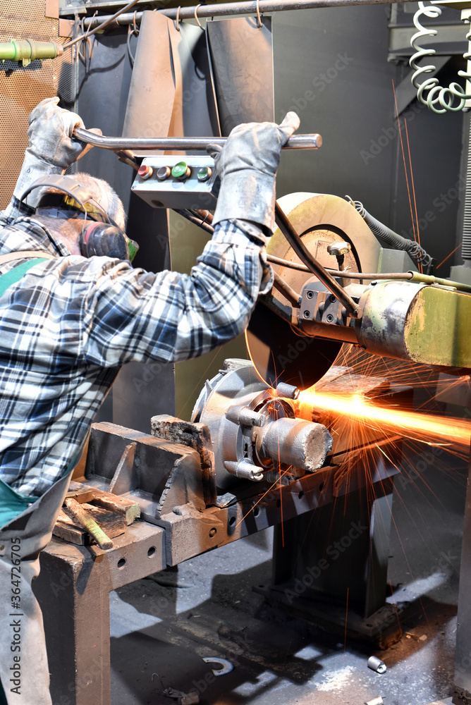 workers in safety clothing sanding a casting in an industrial company workers in safety clothing sanding a casting in an industrial company