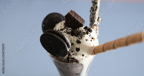 Decorating parfait with Oreo cookies and ice cream and biscuits