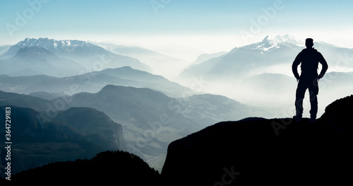 Spectacular layered mountain ranges with valley fog. Man Silhouette reaching summit enjoying freedom. © Drepicter
