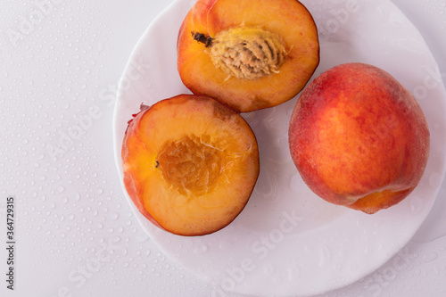 Nectarine peaches with a slice and leaves on a white background
