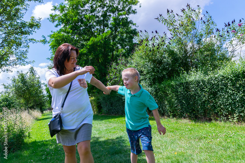 Happy mother and son with down syndrome they walk together in the park.