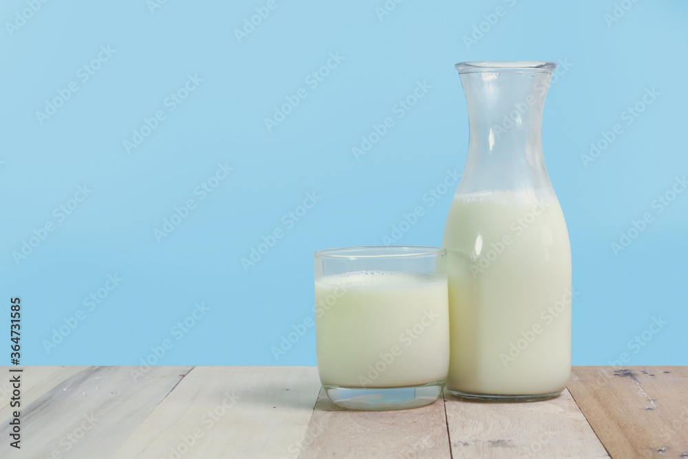 A bottle of rustic milk and glass of milk on a wooden table A bottle of rustic milk and glass of milk on a wooden table