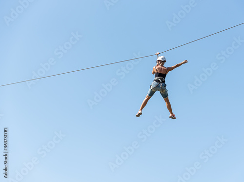 Low angle view of young woman riding on zip line against sky