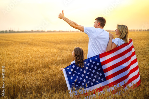 Back view of a unrecognizable Happy family in wheat field with USA, american flag on back. photo