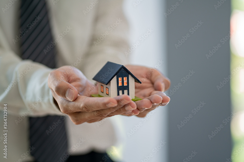 Small toy house in hands.