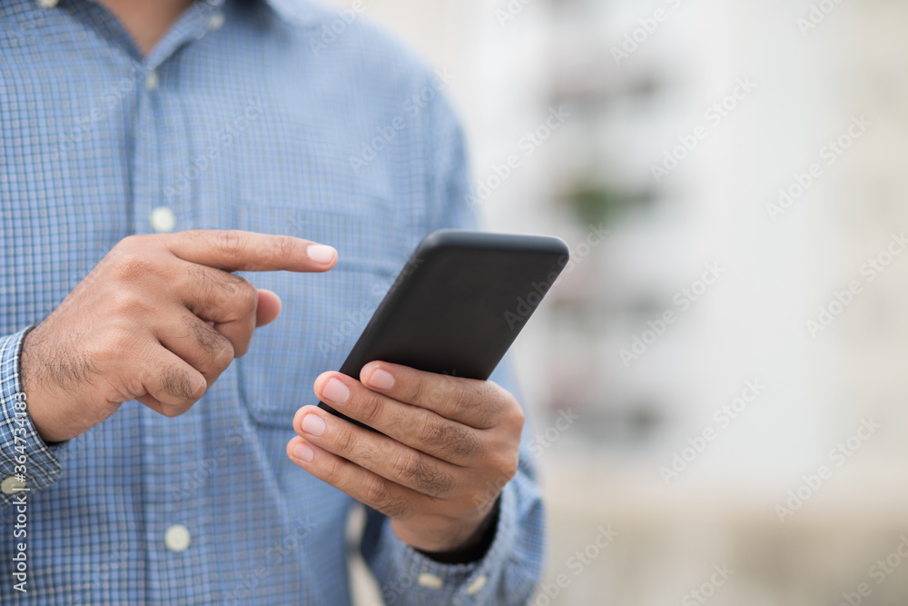 Close up male hands holding using black smartphone on city background. Close up male hands holding using black smartphone on city background.