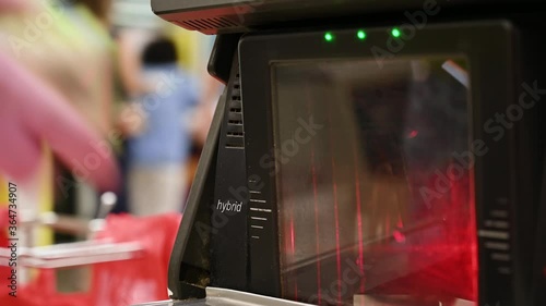 A woman in protective gloves scans products at the self-checkout counter in the hypermarket. New normal.