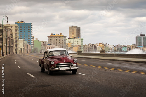 Photography Old car on Malecon street of Havana with storm clouds in background
