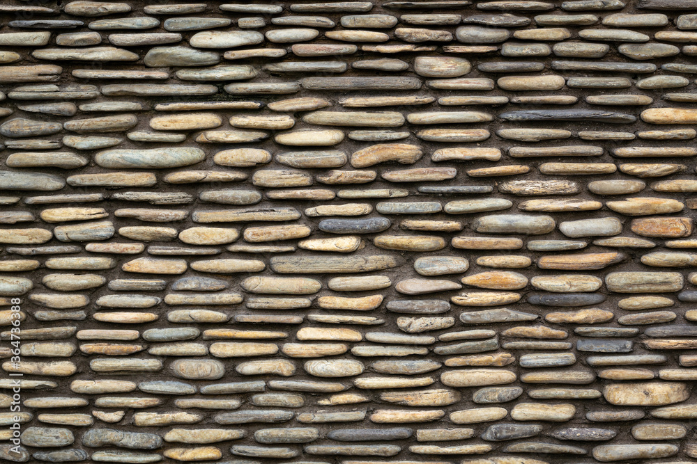 The wall made of yellow round stones. Walls made of pebbles, images for background