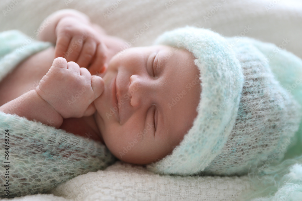 Cute newborn baby in warm hat lying on white plaid, closeup Cute newborn baby in warm hat lying on white plaid, closeup