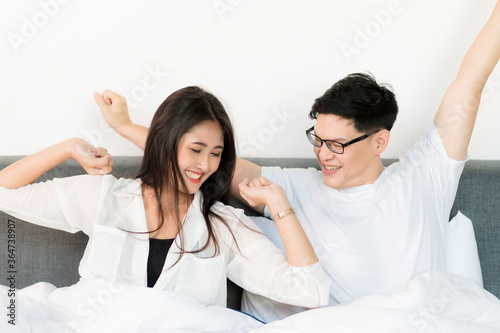 Young asian couple love man and woman woke up in morning on the bed and happy moment. © Nopphon