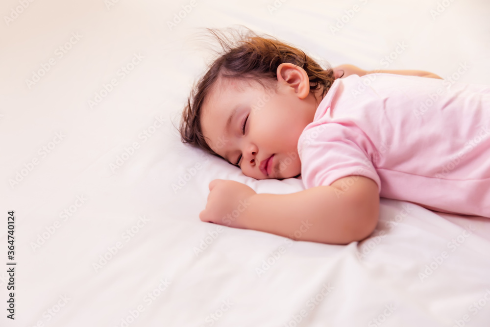 Adorable innocent baby girl sleeping on bed with good dream. Cute mixed race infant baby get deep sleep and peaceful. Lovely toddler girl wear pink baby dress. Child has lovely face. copy space Adorable innocent baby girl sleeping on bed with good dream. Cute mixed race infant baby get deep sleep and peaceful. Lovely toddler girl wear pink baby dress. Child has lovely face. copy space
