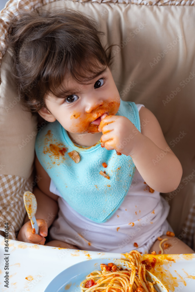Adorable little toddler girl or infant baby eating delicious food with tomato sauce and sucking finger. Funny cute infant girl get hungry and eating food by herself. Mix race daughter get dirty Adorable little toddler girl or infant baby eating delicious food with tomato sauce and sucking finger. Funny cute infant girl get hungry and eating food by herself. Mix race daughter get dirty