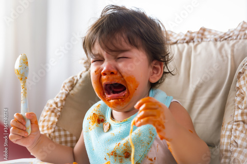 Photos Adorable little toddler girl or infant baby crying when unsatisfied when finished eating food on baby chair