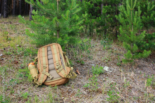 A tourist backpack lies on the ground in the forest