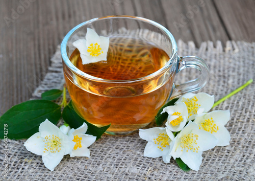 Jasmine tea in a glass cup and fresh flowers on old wooden table.Healthy drink diet or herbal medicine concept.Selective focus.