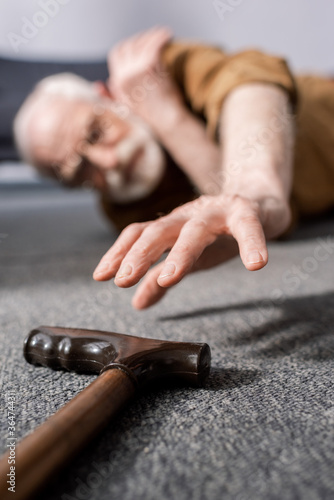 Φωτογραφία selective focus of helpless senior man lying on floor and trying to get walking