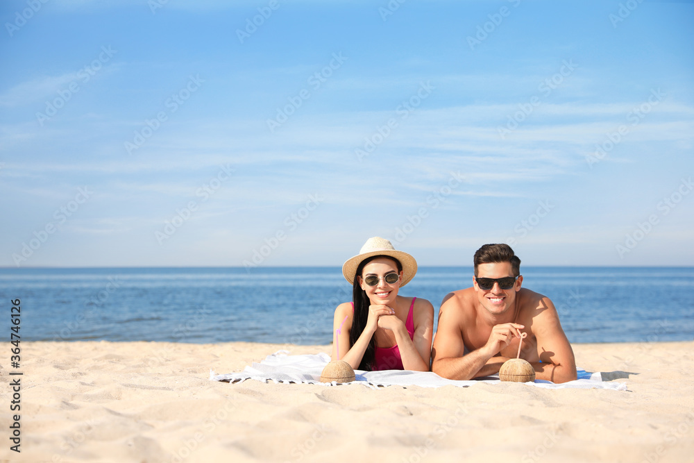 Happy couple with cocktails on sunny beach at resort. Space for text Happy couple with cocktails on sunny beach at resort. Space for text