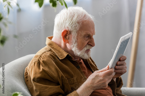 selective focus of angry senior man using digital tablet