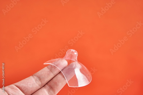 Two fingers holding up a nipple shield. photo