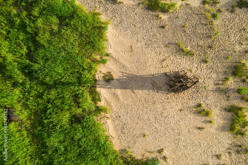 Midsummer celebration preparation. Drone view of woodpile of dry branches on the sand. Green grass.