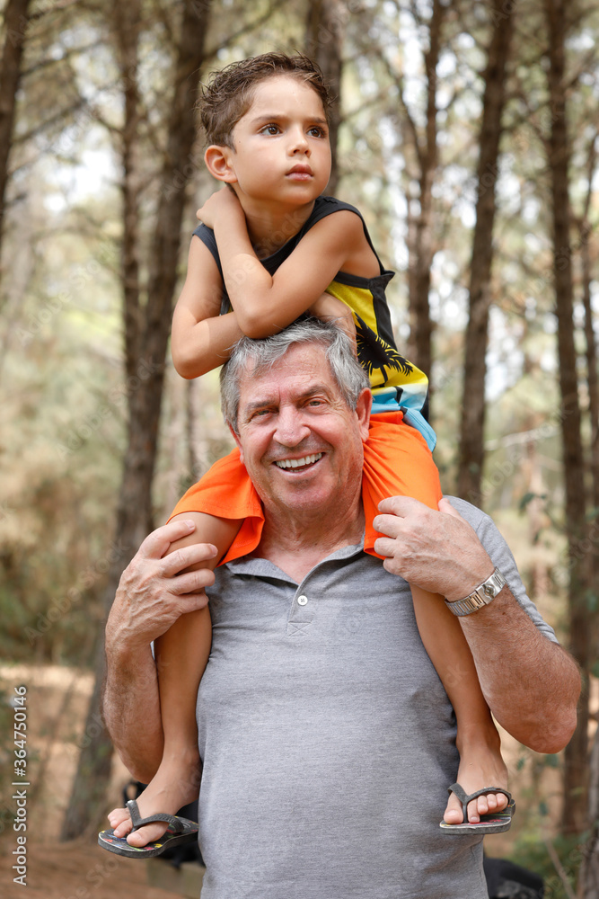 bambino biondo e √® felice perch√© preso in braccio da suo nonno bianco dentro un parco naturale