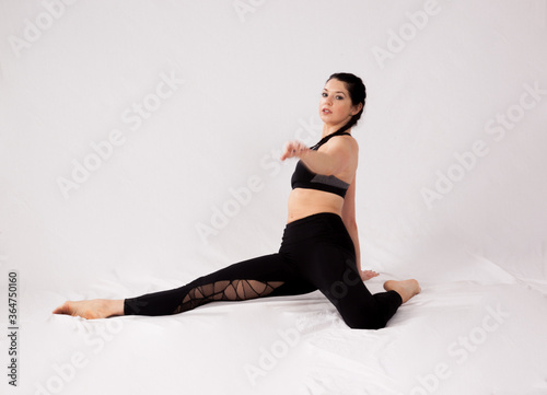 Pretty woman in a black outfit stretching on the floor