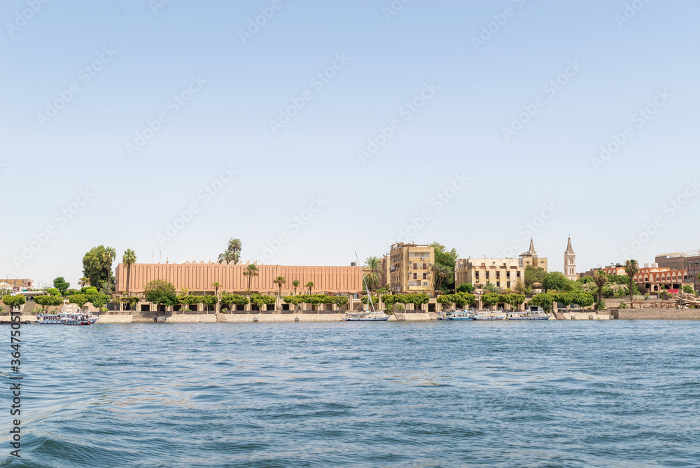 Luxor, Egypt: Panorama of river Nile in Luxor city, view from a boat. Residental buildings and sailboats.