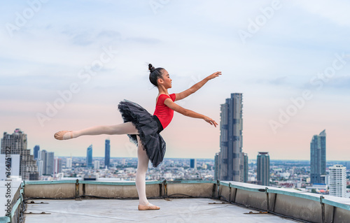 Young Ballerina  dancers with strong legs on the roof of the building background with the sky and cloud. The dance with a delicate style is beautiful  creating an impression and success.