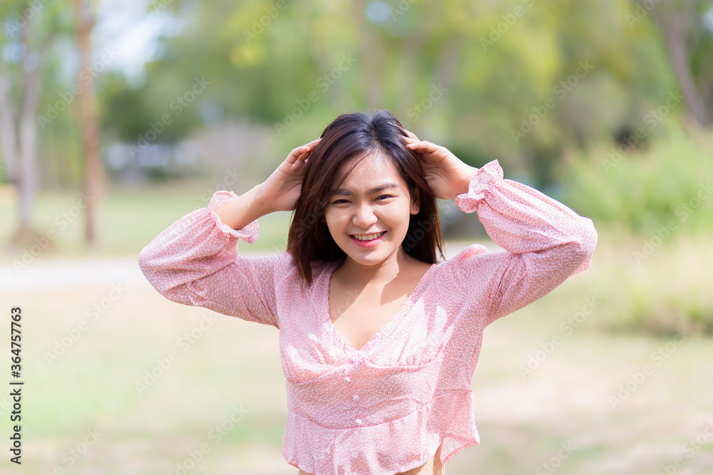 Beautiful Asian women in red dresses and blue jeans standing in the garden. Portrait of asian woman is smiling on the green grass. Beautiful Asian women in red dresses and blue jeans standing in the garden. Portrait of asian woman is smiling on the green grass.