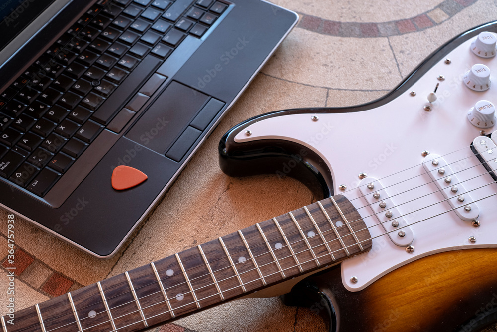 electric guitar next to a laptop with a pick online guitar lessons - obrazy, fototapety, plakaty 