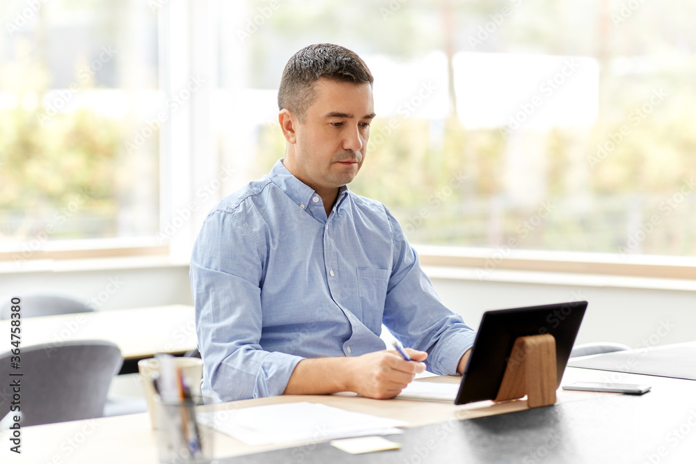 remote job, business and people concept - middle-aged man with tablet pc computer working at home office remote job, business and people concept - middle-aged man with tablet pc computer working at home office