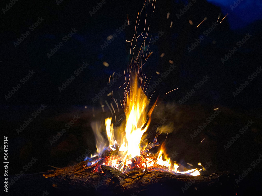 Flaming bonfire with sparks and particles in front of the forest at night. Flaming bonfire with sparks and particles in front of the forest at night.
