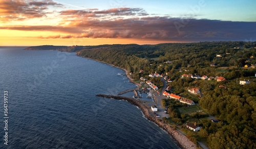 Blick auf den Hafen der dänischen Ortschaft Vang auf der Insel Bornholm in Richtung der alten Festung Hammershus bei einem goldenen Sonnenuntergang vor Wolken im Sommer.