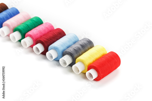 Colorful cotton craft sewing threads multicolored in a row isolated on a white background.