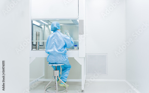 Unidentified microbiologist is testing the sample under the laminar air flow cabinet in the clean room of quality control laboratory in pharmaceutical industry.