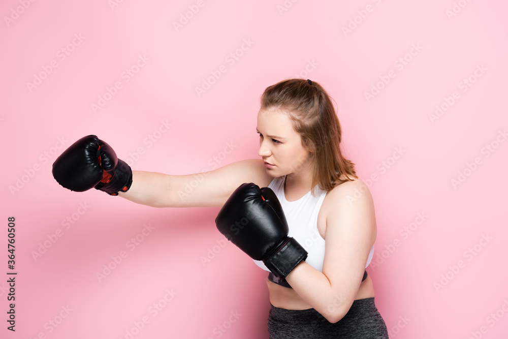 concentrated size plus girl in sportswear boxing on pink