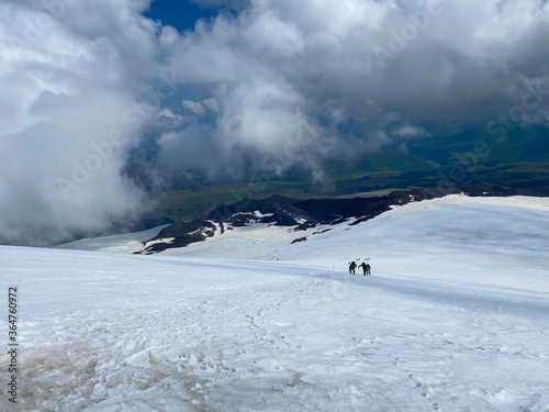 Climbers with a backpack and trekking poles walk along a snowy path. © chekart