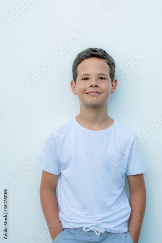 Handsome boy with white shirt smiling on white wall background