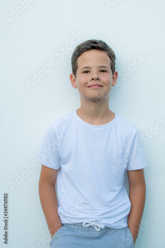 Handsome boy with white shirt smiling on white wall background