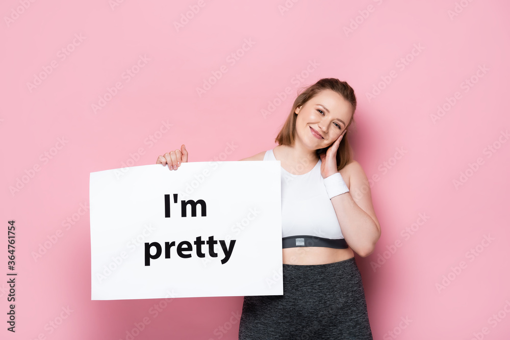smiling overweight girl holding placard with i am pretty inscription on pink smiling overweight girl holding placard with i am pretty inscription on pink